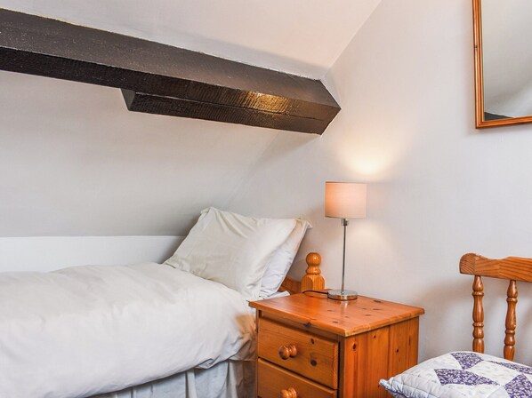 A bedroom with a bed, a wooden nightstand with a lamp, and a headboard.