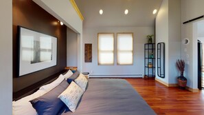 Relax in this serene bedroom with a large bed, framed artwork, and natural light pouring in through the windows.