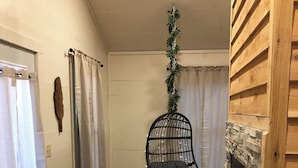 Une pièce avec un fauteuil suspendu, une cheminée et une porte dotée d’un porte-serviettes.