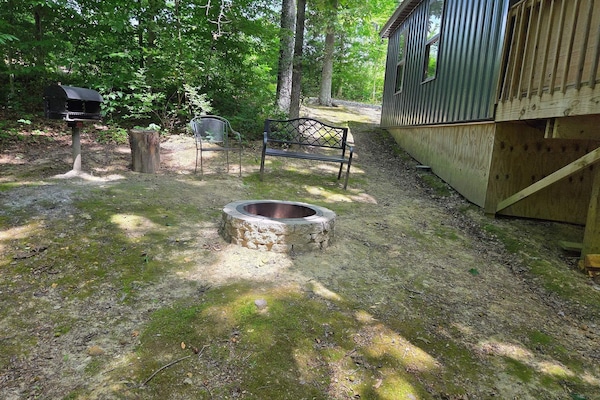 Stone fire pit, bench, and grill in the yard