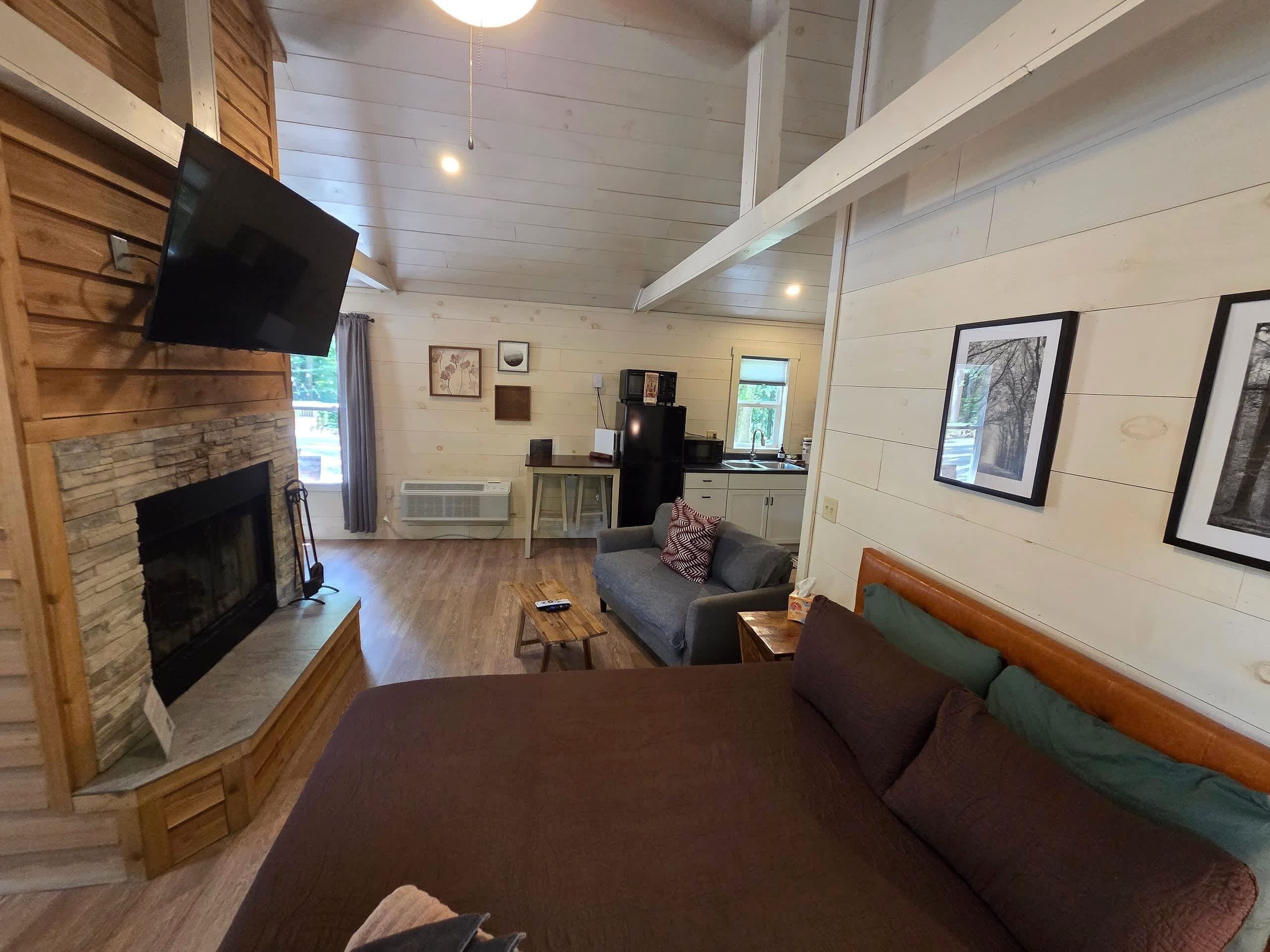 A cozy room with a fireplace, a sofa, a bed, and a television.
