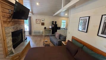 A cozy room with a fireplace, a sofa, a bed, and a television.