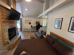 Una habitación acogedora con chimenea, un sofá, una cama y un televisor.