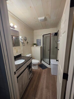 Ein kleines Badezimmer mit Waschbecken, Toilette und Duschbereich.
