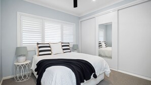 Une chambre à coucher avec un lit, des tables de chevet, un miroir et une armoire.