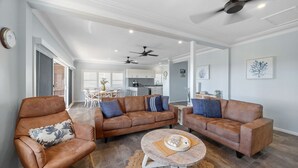 Un salon spacieux avec des canapés en cuir, une table basse et des ventilateurs de plafond.