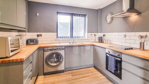 Een kleine keuken met een wasmachine, een inbouwoven en een magnetron.