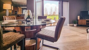 Een moderne eetruimte met een glazen tafel, lederen stoelen en een fles champagne.