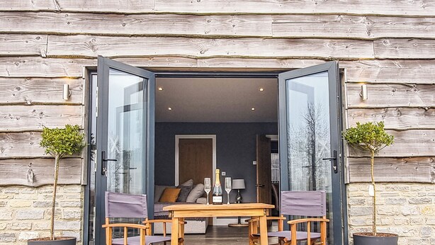 Een open doorgang naar een eetgedeelte met een tafel en stoelen, omlijst door twee potplanten.