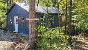 A small cabin labeled 'The Hummingbird' surrounded by trees. - Hummingbird at Avenwood Cabins (New Straitsville)