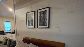 A bedroom with a wooden headboard, a bed with white and red bedding, and two framed pictures on the wall.