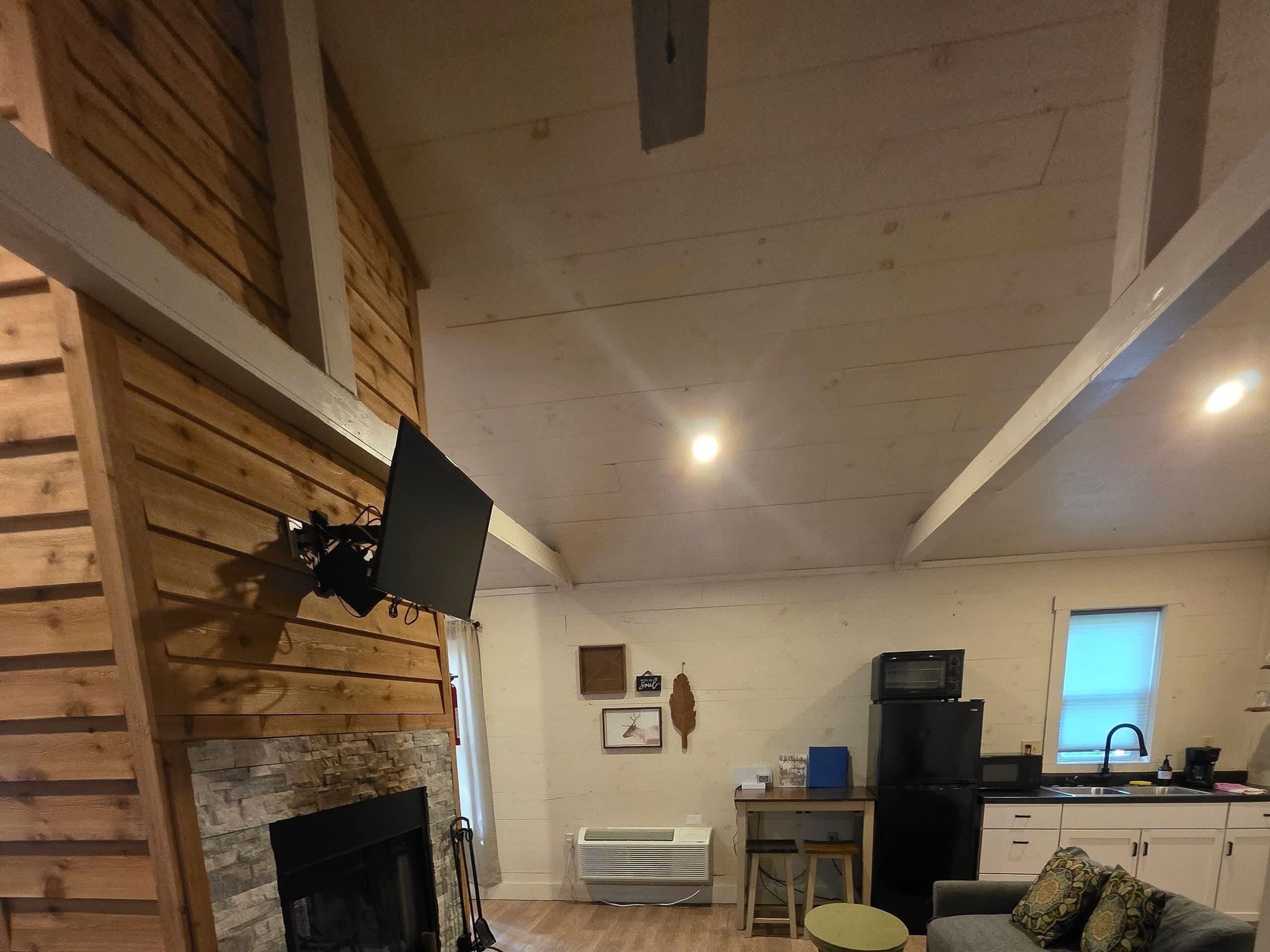 Een gezellige kamer met een open haard, een kitchenette en een eettafel.