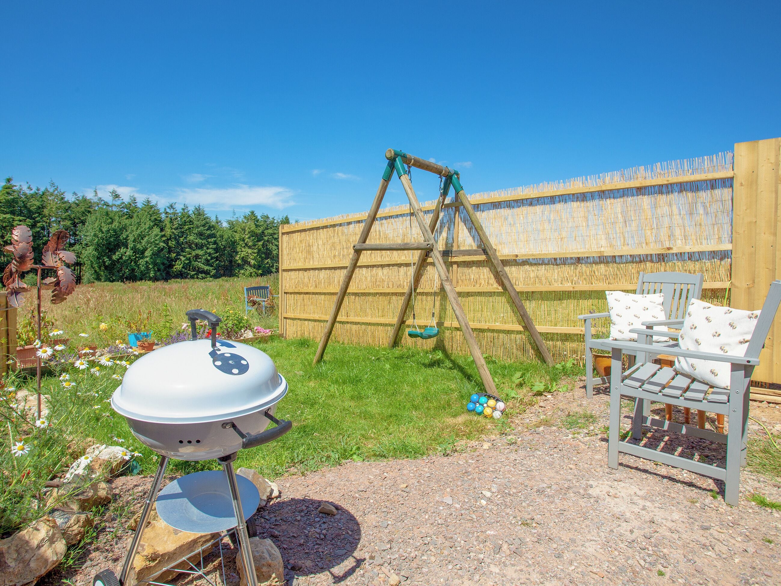 A backyard with a barbecue grill, a swing set, and outdoor seating.