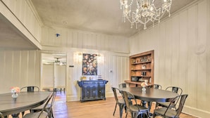 A dining area with a large wooden table and chairs, a chandelier, and a kitchen area with wooden cabinets and a refrigerator. - Stunning historic home w/ large rooms. Close to attractions. Kid & pet friendly! (Sellers)