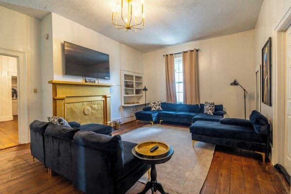 A living room with a fireplace, two sofas, a TV, and a chandelier.