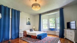 A bedroom with a bed, a dresser, a television, and a window with curtains. - Stunning historic home w/ large rooms. Close to attractions. Kid & pet friendly! (Sellers)