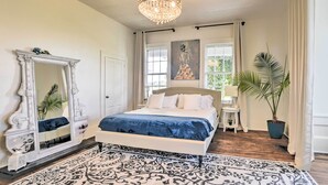 A bedroom with a bed, a large mirror, a chandelier, a painting, and a potted plant. - Stunning historic home w/ large rooms. Close to attractions. Kid & pet friendly! (Sellers)