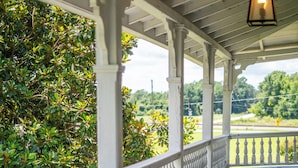 A covered porch with white balustrades, a hanging lantern, and a view of greenery. - Stunning historic home w/ large rooms. Close to attractions. Kid & pet friendly! (Sellers)