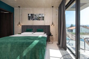 Un dormitorio moderno con una cama grande, una pintura de un paisaje urbano y un balcón con vistas.
