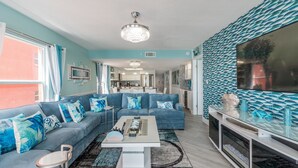 Una sala de estar moderna con un sofá azul, una mesa de centro y un televisor sobre un mueble.