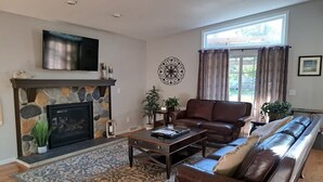 Ein Wohnzimmer mit Kamin aus Stein, einer Ledersofa und einem Flachbildfernseher.