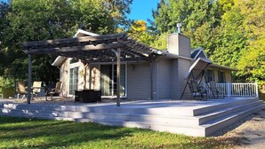 Ein Bungalow mit überdachter Terrasse, einer Veranda mit Schaukel und einer Garage.