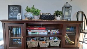 Eine Holzkabine mit Glastüren, gefüllt mit Büchern, Spielen und gewebten Körben.