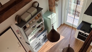A kitchen with a wooden table, hanging light fixture, and a view of the balcony. - CadeFe Loft loft in historic downtown (La Spezia)