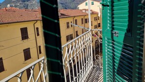 A balcony with a view of a mountain, buildings with red-tiled roofs, and a green door. - CadeFe Loft loft in historic downtown (La Spezia)