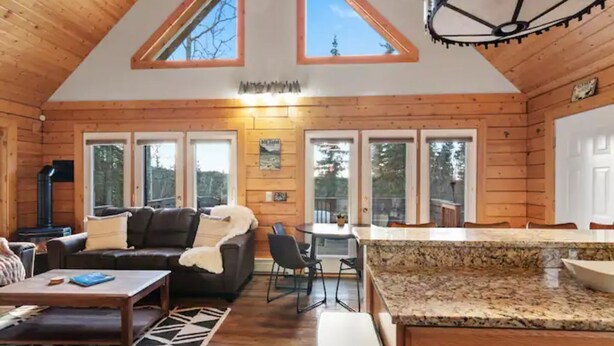 A cozy cabin interior with a wooden interior, a dining area, and a kitchen with granite countertops.