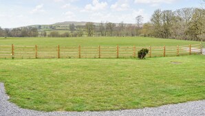 A fenced field with a gravel path leading to a wooden fence.