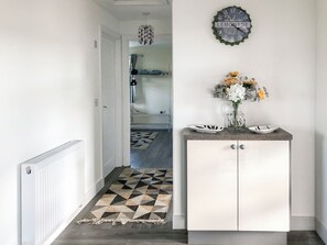 A hallway with a patterned rug, a cabinet with decorative plates, and a wall clock. - Ballygroggan Bungalow - UK38174 (Machrihanish, near Campbeltown)