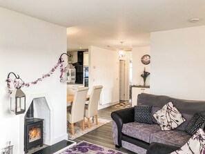 A modern living room with a fireplace, a sofa, a dining area, and a kitchen in the background. - Ballygroggan Bungalow - UK38174 (Machrihanish, near Campbeltown)