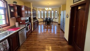 Una cocina con armarios de madera, un refrigerador de acero inoxidable y un comedor con candelabro.