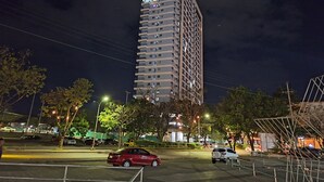 A tall, modern building with multiple balconies, surrounded by trees and streetlights. - Bright Studio Sleeps 3 With Parking and City View (Cagayan de Oro)
