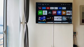 A flat-screen TV mounted on a wall displaying various streaming apps. - Bright Studio Sleeps 3 With Parking and City View (Cagayan de Oro)