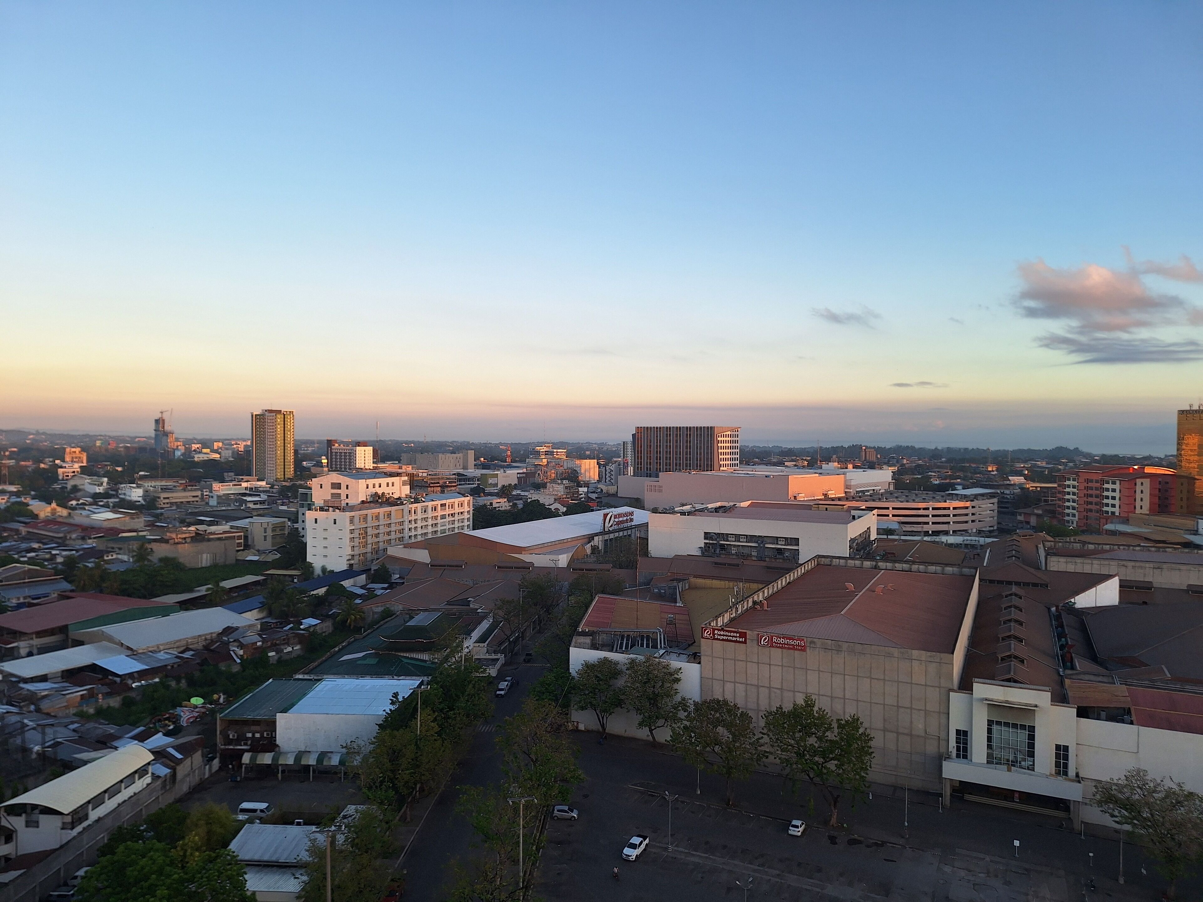 A cityscape with various buildings, including a large parking garage and a commercial building with signage.