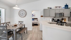 A modern kitchen with grey cabinets, a microwave, and a stove. There is a dining area with a wooden table and chairs, and a clock on the wall. - **EXCLUSIVE 3-bedroom w/heated private pool** (Palm Coast)