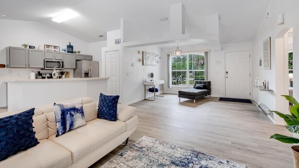 A modern living room with a beige sofa, a coffee table, and a view of the kitchen. - **EXCLUSIVE 3-bedroom w/heated private pool** (Palm Coast)