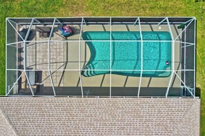 An aerial view of a swimming pool with a metal frame, surrounded by a paved deck.