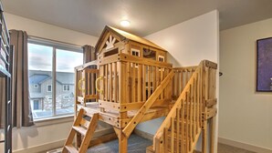 Una casita de madera con escalera en un espacio luminoso con ventana grande y vistas a edificios.