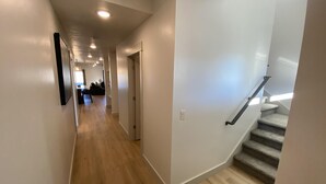 Un interior moderno con piso de madera, una escalera y un pasillo que lleva a una sala de estar.