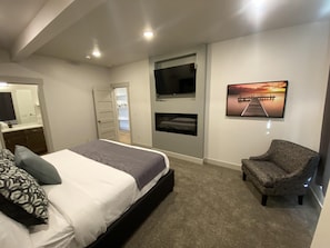 A bedroom with a bed, a chair, a TV, a painting, and a closet. - Townhome 32 at Waterdance - sleeps 16 4B/4.5BA, year-round indoor pool/hot tub! (Garden City)