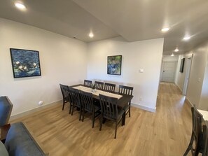 A dining area with a rectangular table and six chairs, a potted plant, and two paintings on the walls. - Townhome 32 at Waterdance - sleeps 16 4B/4.5BA, year-round indoor pool/hot tub! (Garden City)