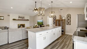 A modern kitchen with white cabinetry, a central island, and a dining area with a sofa and chairs. - Ridge View - Hot Tub-Fireplace-Fire Pit (Hiawassee)