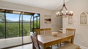 A dining room with a large table, chairs, and a chandelier. There is a large window with a view of greenery and mountains. - Ridge View - Hot Tub-Fireplace-Fire Pit (Hiawassee)
