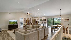 A spacious living room with a sectional sofa, a flat-screen TV, and a dining area with a table and chairs. - Ridge View - Hot Tub-Fireplace-Fire Pit (Hiawassee)
