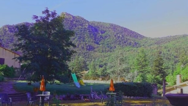 Un espace extérieur aménagé en terrasse, avec un sol en pierre, des sièges et une vue sur une montagne.