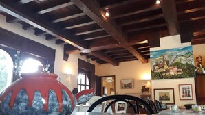 Un espace repas agrémenté de poutres en bois, une table avec des chaises, un vase et des œuvres d’art mural.
