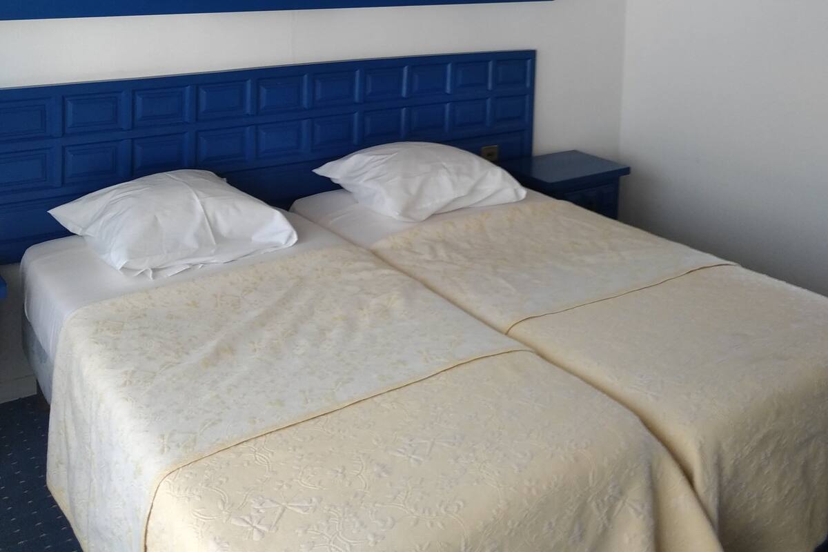 Une chambre d’hôtel avec un lit, une table de chevet et un tableau encadré au mur.